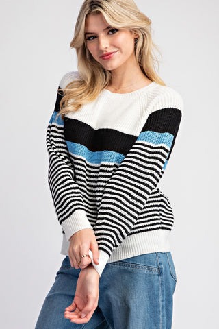Woman wearing a striped sweater with black, white, and blue colors on a light gray background