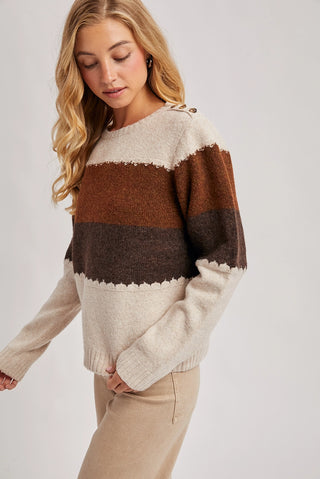 Woman wearing a color-blocked sweater with brown and beige tones on a plain background