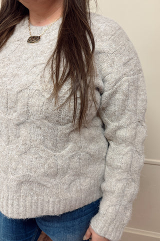 Person wearing a textured gray sweater against a neutral background