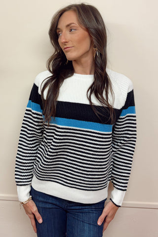 Woman wearing a striped sweater with blue and black stripes against a beige background