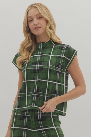 Woman wearing a green plaid top and skirt on a plain background