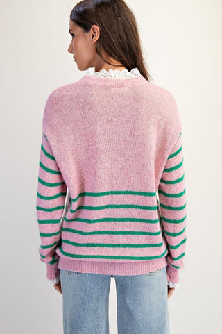 Person wearing a pink and green striped sweater with a plain background
