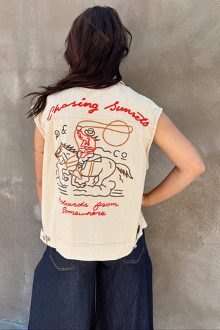 Person wearing a sleeveless embroidered vest against a concrete wall