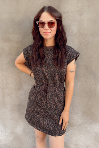 Woman wearing a patterned dress and sunglasses against a plain background