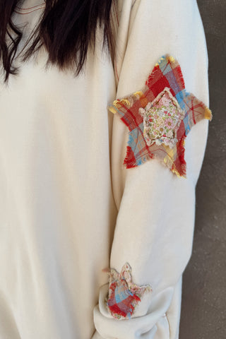 Close-up of a white garment with colorful patchwork designs on the sleeve.