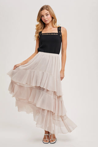 Woman wearing a black top and layered beige skirt on a white background