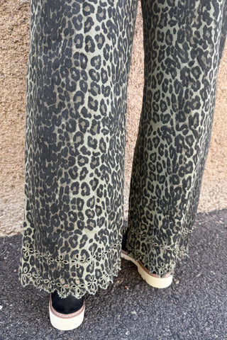Person wearing leopard print pants on a pavement.