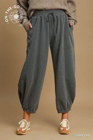Person wearing charcoal gray sweatpants on a brown background