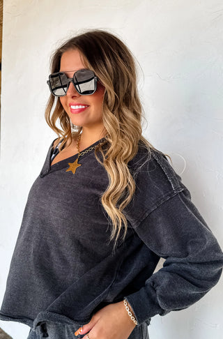Woman wearing a dark gray oversized sweater with sunglasses and a white background