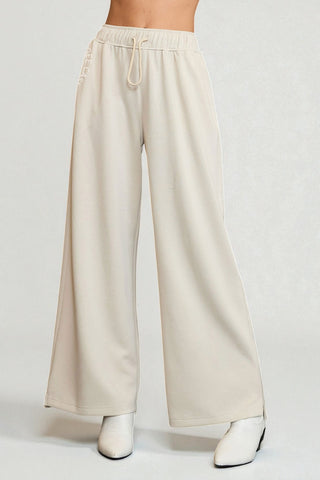 Beige wide-leg pants worn by a person on a white background