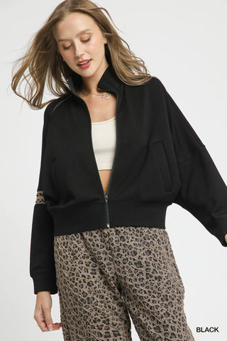 Woman wearing a black jacket and leopard print pants on a white background