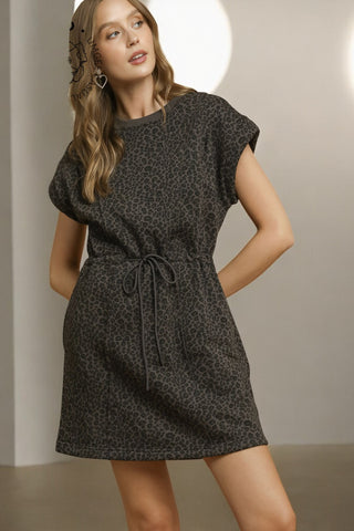 Woman wearing a black patterned dress against a neutral background