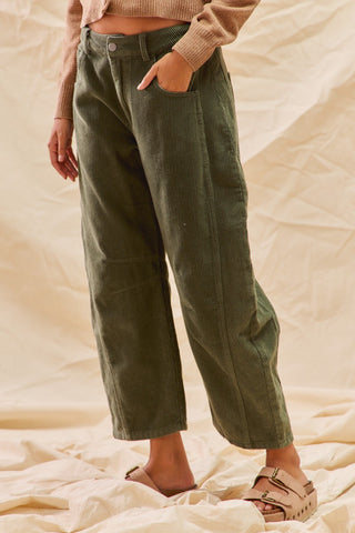 Person wearing green corduroy pants on a beige background