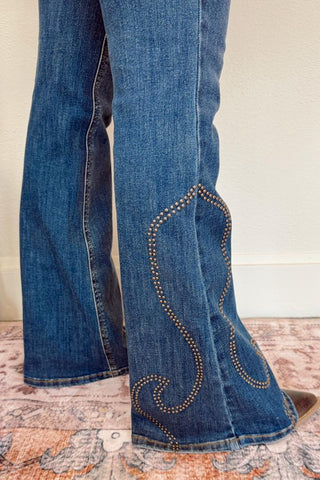 Close-up of blue jeans with decorative stitching on a patterned surface