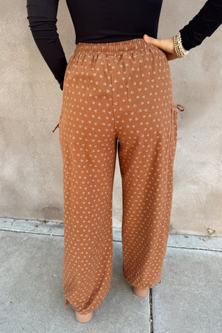 Person wearing brown patterned pants against a plain background