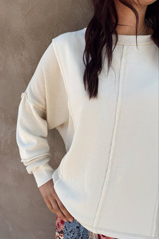 Person wearing a white zip-up sweatshirt against a neutral background