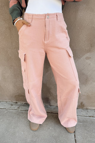 Person wearing pink cargo pants against a beige wall.