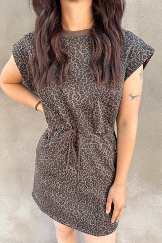 Person wearing a leopard print dress against a neutral background