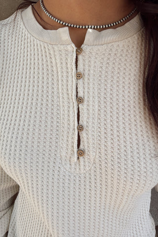 Close-up of a textured beige sweater with buttons