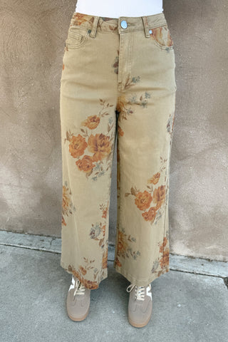 Person wearing floral-patterned beige pants against a plain background