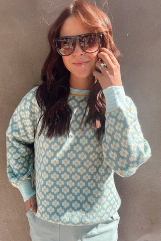 Woman wearing a floral patterned shirt and sunglasses against a plain background