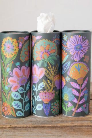 Three cylindrical tissue paper holders with floral designs on a wooden surface.