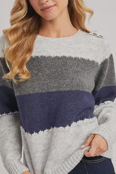 Woman wearing a gray and navy striped sweater on a plain background