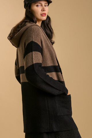 Woman wearing a black and brown striped hoodie against a beige background