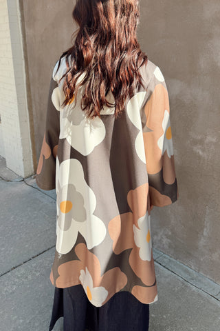 Person wearing a patterned coat standing against a wall.