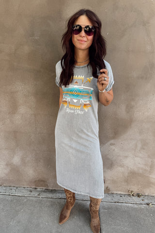 Woman wearing a graphic t-shirt dress against a plain wall