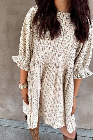 Person wearing a patterned dress against a plain background