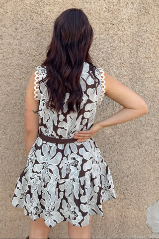 Woman wearing a black and white lace dress against a beige wall.