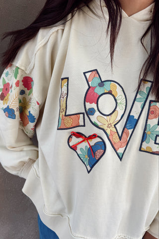 White hoodie with colorful 'LOVE' design on a plain background