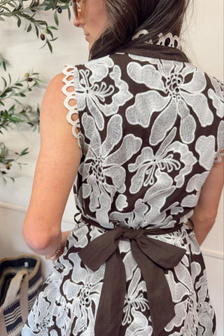 Woman wearing a brown and white floral dress with a bow detail.