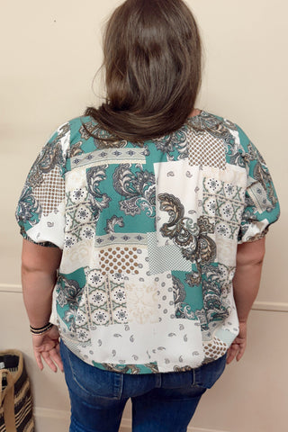 Person wearing a patterned blouse with a neutral background