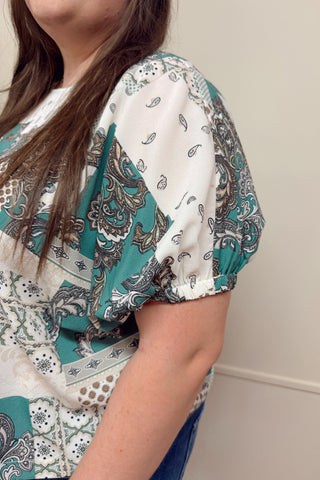 Person wearing a patterned blouse with a neutral background
