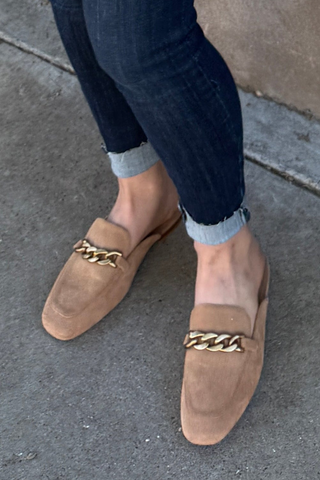 Person wearing a white jacket with floral patterns on a concrete wall.