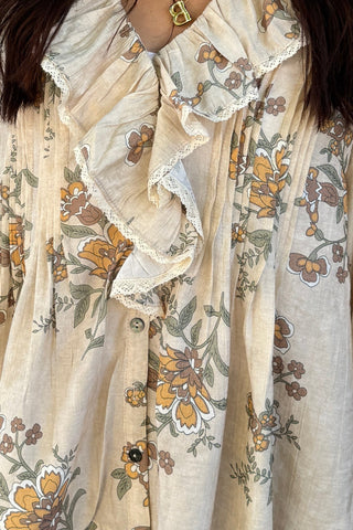 Woman wearing a floral blouse and sunglasses on a textured wall background
