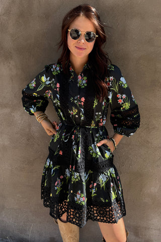 Woman wearing a floral dress with sunglasses on a plain background