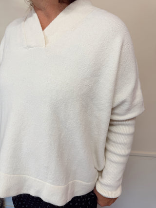 Person wearing a white sweater against a plain background