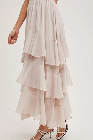 Long, layered beige skirt worn by a person on a white background