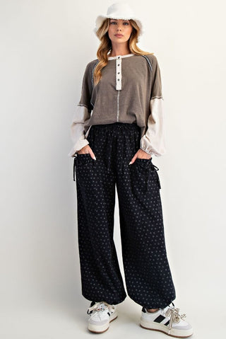 Woman wearing a brown and white top with black patterned pants on a white background