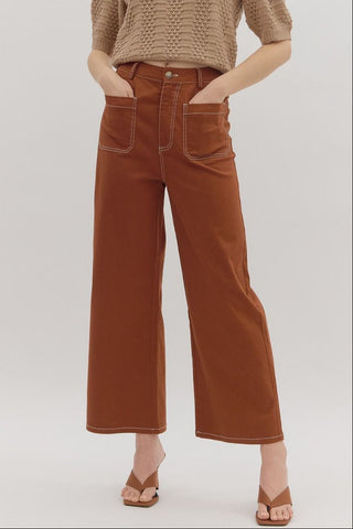 Woman wearing a brown knitted top and wide-leg brown pants on a white background